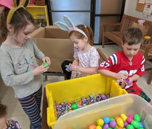 Youth volunteers fill plastic eggs with candy for the Bunny Basket program