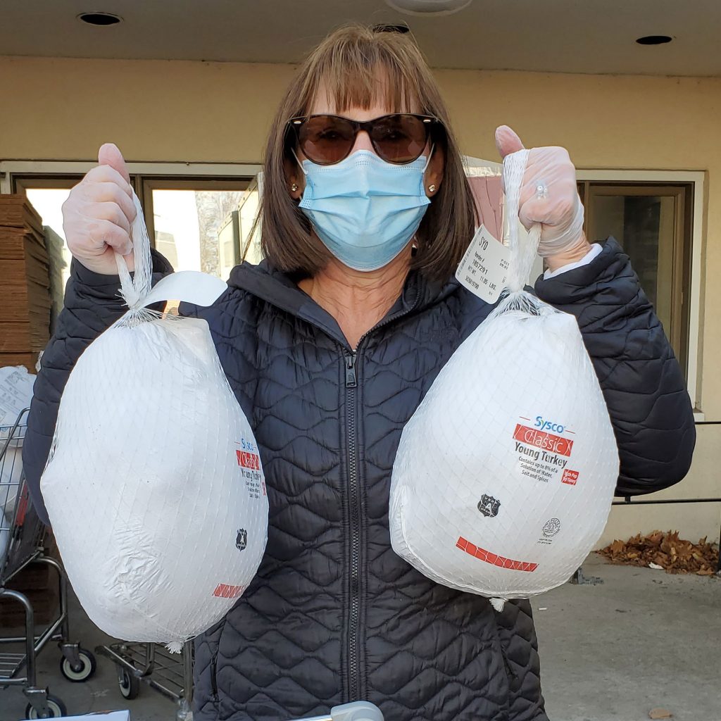 Volunteer holding two donated turkeys