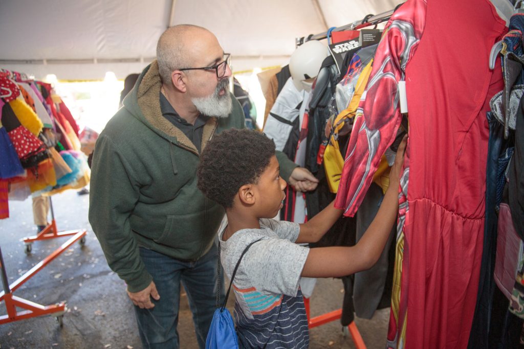 A volunteer assists a child in selecting a Halloween costume at Interfaith's 2019 Costume Giveaway.