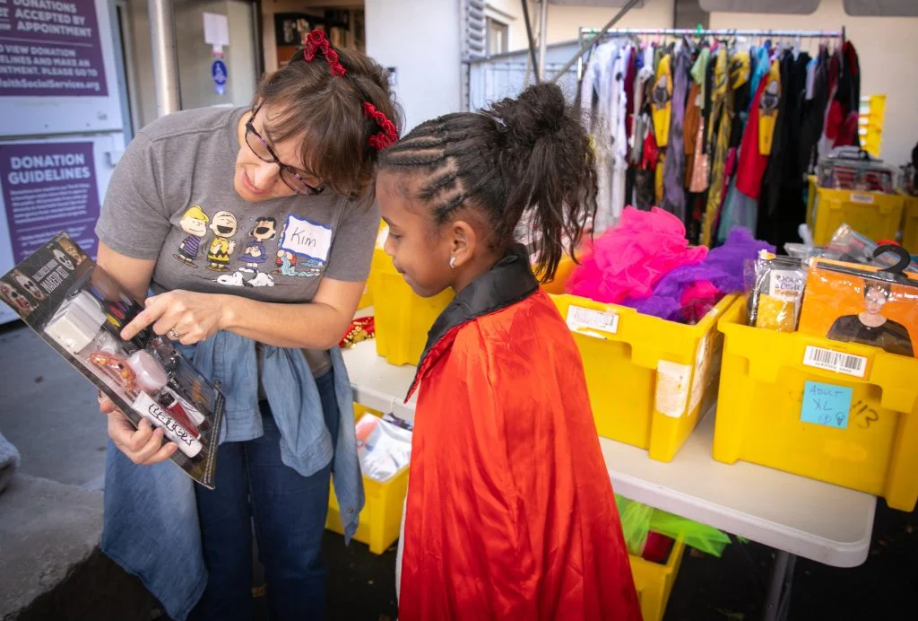 Interfaith Social Services volunteer Kim DeVito, of Taunton, left, helps a child find a makeup kit to go with her costume