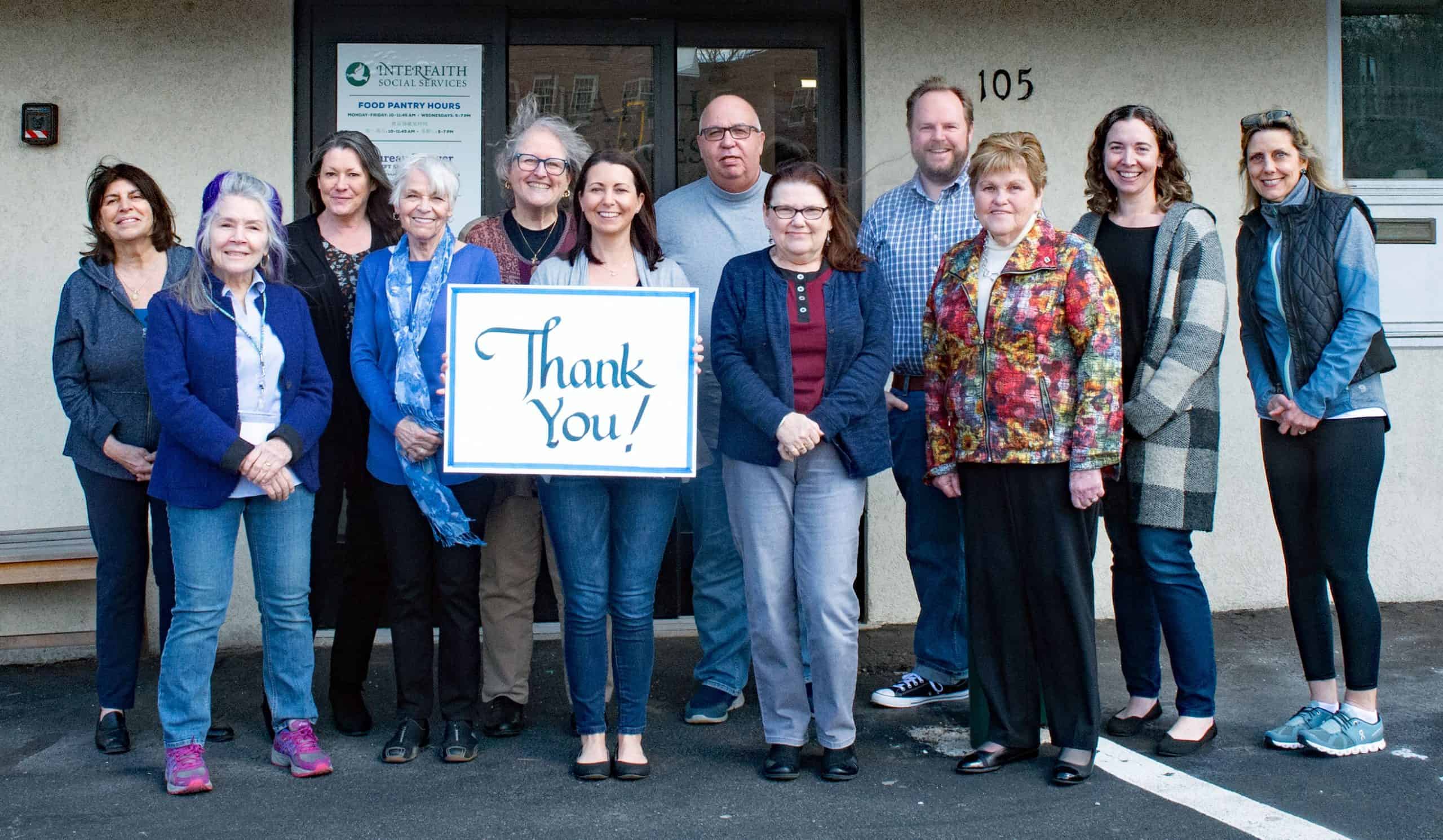 Interfaith Staff holding Thank you sign in front of building