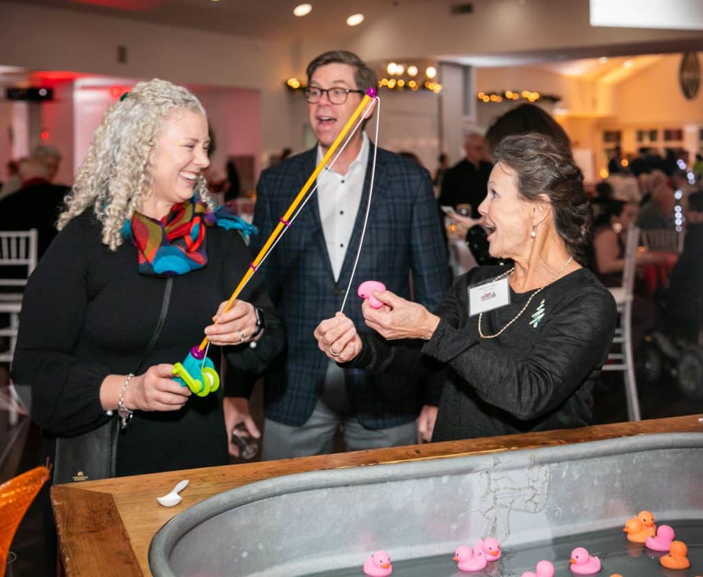 Nadine Steffan, left, of Quincy, reacts to selecting a winning duck at the Carvalho Group Dunkin for Ducks game at Interfaith Social Services’ Dec. 6 Feed the Hungry Gala at Granite Links. Gala guests had the opportunity to play games and win prizes at the annual fundraising event. Alex Steffan, center, and Interfaith volunteer Gayle Davidson, right, both of Quincy, looked on. Credit –Matt Teuten Photography