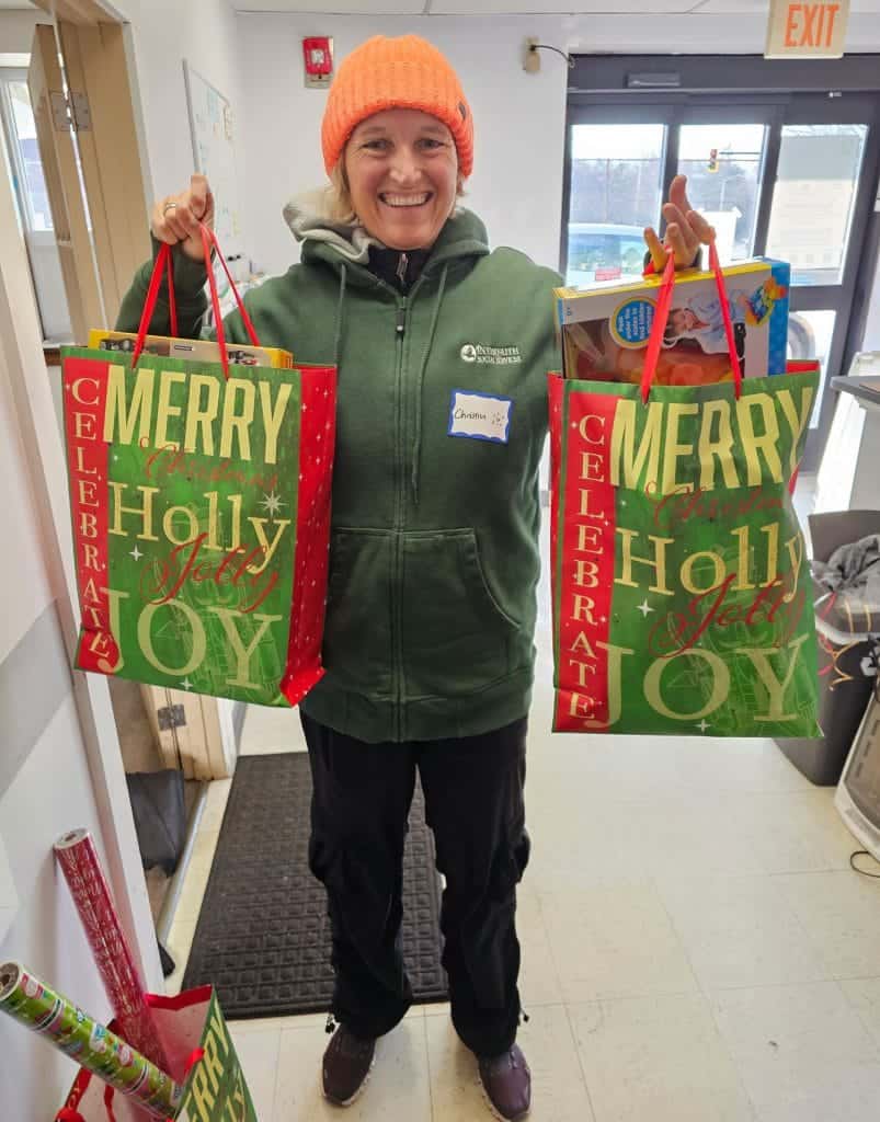 Interfaith Social Services volunteer Christin Eigenmann, of Hingham, holds up a couple of bags of gifts that were donated to the organization’s Help for the Holidays program. Thanks to generous community donors, Interfaith was able to provide more than 6,000 gifts to 1,000 South Shore children in need this holiday season. Credit – Interfaith Social Services Courtesy Photo