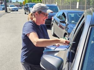 Interfaith volunteer at car checking in a client
