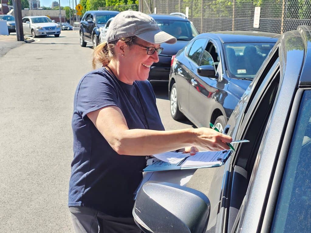 An Interfaith volunteer checks in a food pantry client on a busy weekday.