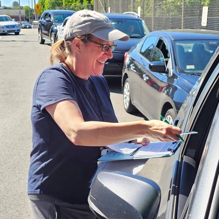 Interfaith volunteer at car checking in a client