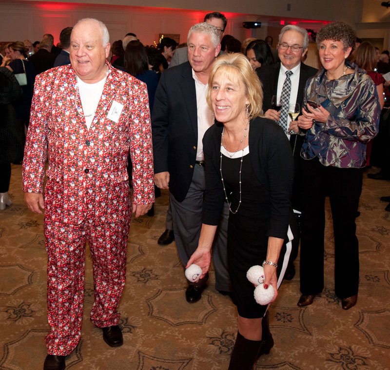 Ron Collins (snowman suit), an Interfaith volunteer , watches as guest Barbara Pyne tries out the Snowball Toss game.